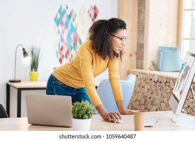 My new startup. Good-looking serious young curly-haired woman holding a pencil and working on her laptop while standing at her table - Shutterstock ID 1059640487