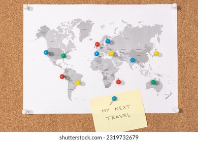 My next travel destination concept. Pushpins on world map on Corkboard and yellow sticky note