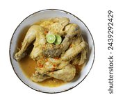 My photo is a bowl of chicken opor or chicken curry, with traditional spices. served in a vintage style bowl. garnished with slices of hot chili sauce, fried onions and lime.