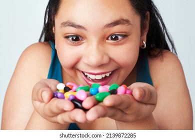 My precious. Studio shot of a cute young girl holding a handful of colorful jelly beans. - Powered by Shutterstock