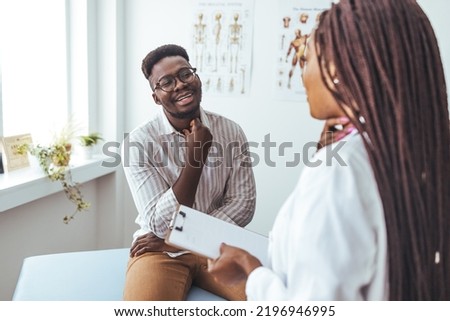 My tonsils feel a little tender. An African American female doctor examines with her fingers, palpates neck and lymph nodes. Pain in the neck. Mixed race doctor and patient. 