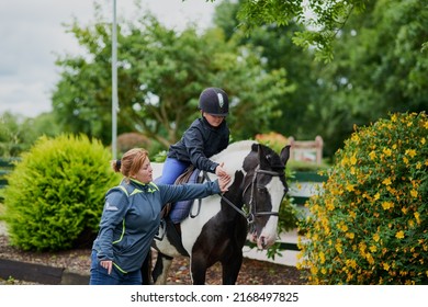 My trainer is helping me succeed. Shot of a horse riding trainer teaching a young girl how to ride a horse outdoors. - Powered by Shutterstock
