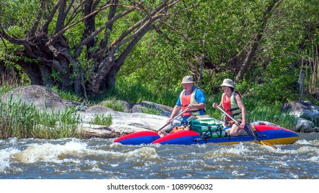 Myhiya, Ukraine - May 1, 2018: Rafting And Kayaking. A Man And A Woman In Old Age Are Sailing On A Rubber Inflatable Boat. Water Splashes Close-up. Extreme Sport. Ecological Water Tourism.