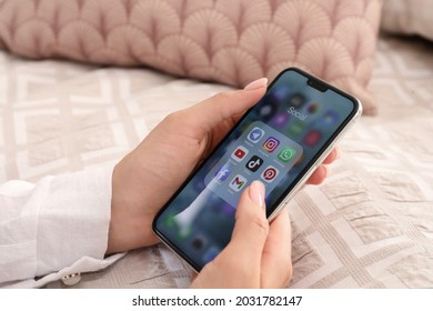 MYKOLAIV, UKRAINE - AUGUST 11, 2021: Woman Using Apple IPhone X At Bed, Closeup. Screen With Different Social Media Icons