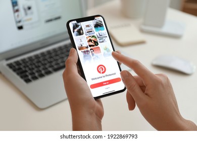 MYKOLAIV, UKRAINE - AUGUST 28, 2020: Woman Holding IPhone 11 With Pinterest App On Screen At Table, Closeup