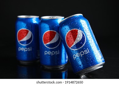 MYKOLAIV, UKRAINE - FEBRUARY 08, 2021: Cans of Pepsi with water drops on black table