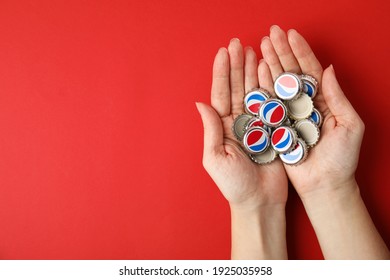 MYKOLAIV, UKRAINE - FEBRUARY 12, 2021: Woman holding Pepsi lids on red background, top view. Space for text