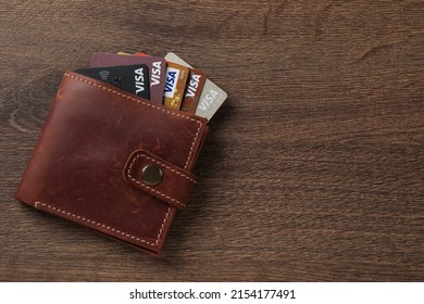 MYKOLAIV, UKRAINE - FEBRUARY 22, 2022: Wallet with Visa credit cards on wooden table, top view. Space for text