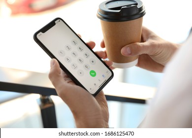 MYKOLAIV, UKRAINE - MARCH 16, 2020: Man Holding IPhone 11 With Keypad On Screen Indoors, Closeup