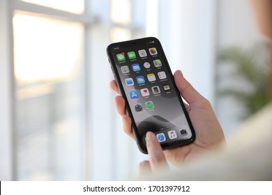 MYKOLAIV, UKRAINE - MARCH 16, 2020: Woman Holding IPhone 11 With Home Screen Indoors, Closeup