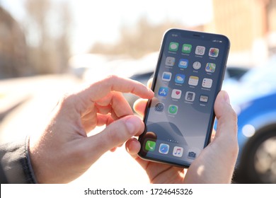 MYKOLAIV, UKRAINE - MARCH 16, 2020: Man holding iPhone 11 with home screen outdoors, closeup