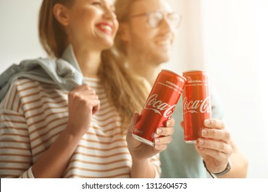 MYKOLAIV, UKRAINE - NOVEMBER 28, 2018: Young couple with Coca-Cola cans indoors. Refreshing drink 