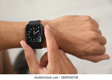 MYKOLAIV, UKRAINE - OCTOBER 04, 2019: Man Using Apple Watch To Check Time On Light Background, Closeup