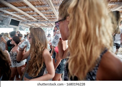 Mykonos, Greece 25 July 2015 Girls Are  In The Beach Party And Drinking Yeni Raki As A Apéritif Which Is A Sweetened, Often Anise-flavoured, Alcoholic Drink From Turkey. Popular In Greece And Balkans