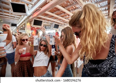 Mykonos, Greece 25 July 2015 Girls Are  In The Beach Party And Drinking Yeni Raki As A Apéritif Which Is A Sweetened, Often Anise-flavoured, Alcoholic Drink From Turkey. Popular In Greece And Balkans