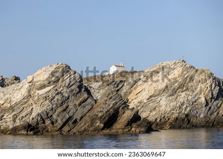 Mykonos, Greece - July 21, 2023: A clifftop cross and church on an island off the shores of Mykonos Town in Greece
