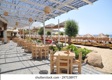 Mykonos, Greece - May 31, 2013 : People Are Sitting At The Cafe Along Paradise Beach, Mykonos, Greece. Mykonos Is The Most Popular Greek Island, Known For Non-stop Party Island.