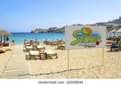 MYKONOS, GREECE - MAY 6 2013:The Famous Super Paradise Beach On The Greek Island Myconos.View Of Golden Sandy Beach, The Sign, Sunbeds, Umbrellas And Blue Sea In A Perfect Summer Holiday Party Place.