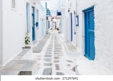 Mykonos, Greece - Traditional whitewashed street of Mykonos town with blue windows and doors on a sunny summer morning. Empty alleyway at sunrise - Powered by Shutterstock