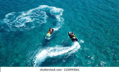Mykonos island , Cyclades / Greece - July 15 2018: Aerial bird's eye view of jet skis cruising in high speed in turquoise clear water beach of Super Paradise