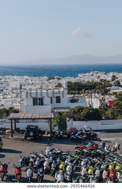 Mykonos Town, Greece -\
September 24, 2019: Rows of motorbikes parked on a parking lot in\
Hora (also known as Mykonos Town), the islands well-preserved port\
and capital.