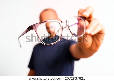 Myopia in mature men is corrected with glasses, a young man holds glasses in his hand.