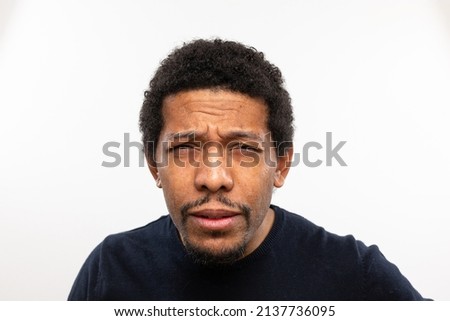 Myopic man without glasses straining his eyes because he can't see well. Squinting face and frowning expression. Isolated against white background
