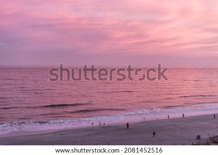 Myrtle Beach with aerial high angle view on Atlantic ocean at sunset twilight dusk with colorful pink sunlight color on water horizon reflection and people walking