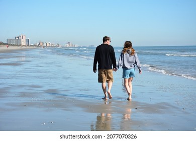 Myrtle Beach South Carolina USA-November 17, 2021. A couple takes a peaceful walk along the ocean while holding hands.