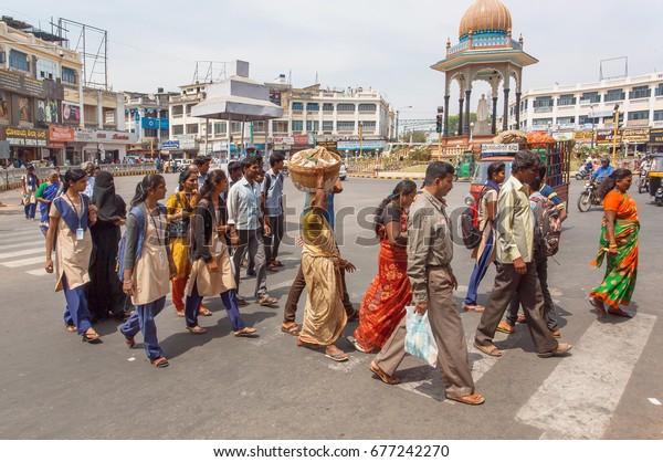 MYSORE,\
INDIA - FEB 20: Indian men and women walking on street with\
pedestrians, on square with crossroad on February 20, 2017.\
Population of Karnataka is 62,000,000\
people