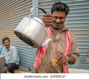 MYSORE, INDIA - FEBRUARY 8, 2013 - Men Pours Cup Hot Milk Tea Indian Style Or Chai For Customers From His Shop Along Street