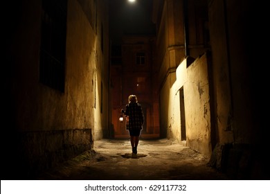 Mysterious Blonde Woman In Elegant Retro Coat With Old Oil Lantern Walking In Old French Street In Paris, Noire Atmosphere, Investigating Crime, Detective Concept