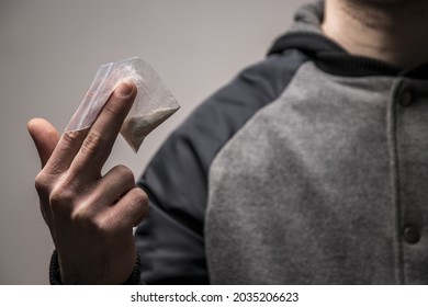Mysterious faceless drug dealer holding a bag of cocaine or heroin. Concept of drug dealing or addiction