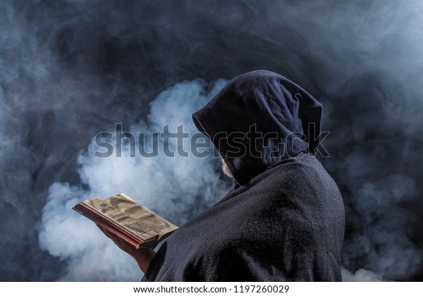 a mysterious\
figure holds a book in his\
hands