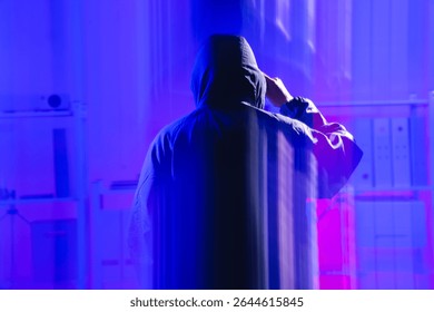 A mysterious figure in a hoodie stands in a digital environment, symbolizing themes of coding and cybersecurity. The ethereal lighting sets a tense atmosphere, representing risks in data protection.