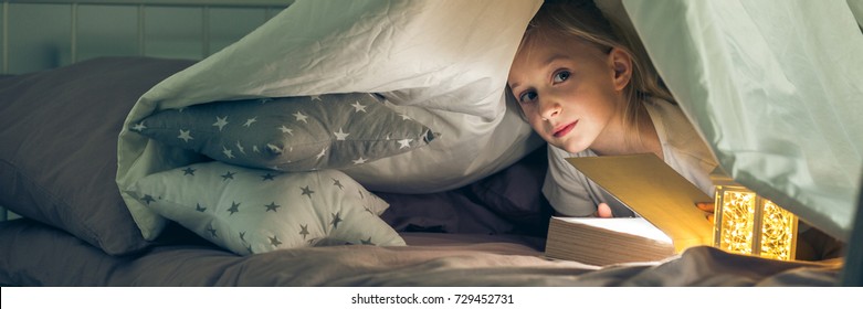 Mysterious Girl Hiding Under The Covers With Book And Torch