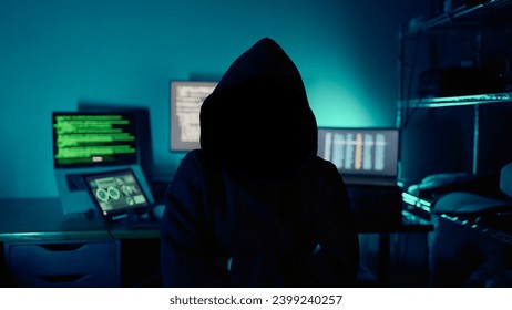 Mysterious hacker sitting at desk in dark atmosphere. A computer programmer or hacker. Anonymous computer hacker. Hacker in dark room. Cyber crime - Powered by Shutterstock