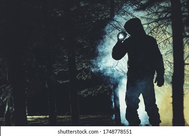 Mysterious Men With Flashlight In His Hand In Dark Foggy Forest. Poacher, Hunter Or Rescuer During Rescue Action.