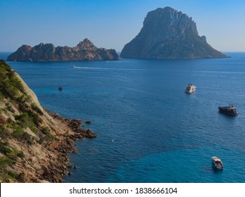 Mysterious and mystical Es Vedra rock next to the famouse Balearic Island of Ibiza in the deep blue Mediterranean Sea surrounded by yachts and boats