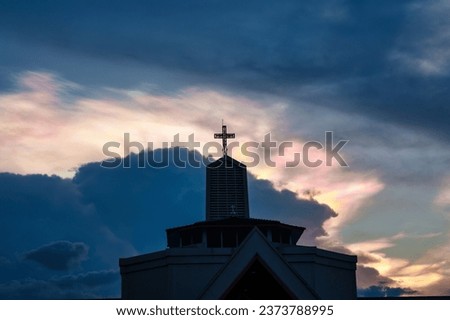 Mysterious polar cloud iridescence phenomenon glowing over christian church and cross shape religious in the evening