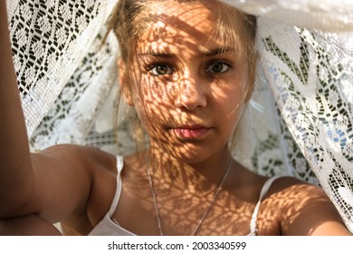 Mysterious Portrait Of A Beautiful Mestizo Young Girl With Light Shadow Pattern On Face. Adorable Charming Green Eyed Female Looking At Camera. Creative Art Shadows From White Lace Sheet At Sunny Day.