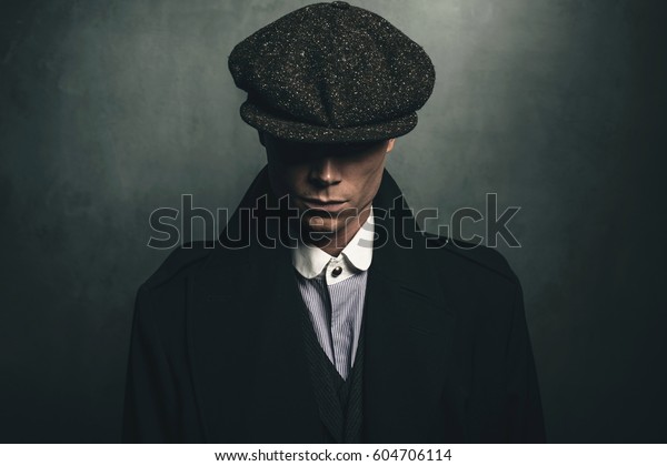 Mysterious portrait of retro 1920s english gangster\
with flat cap.