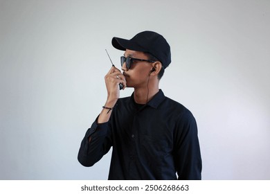 mysterious security forces wearing all black clothing starting from black glasses, hats, shirts are communicating via intercom via walkie talkie isolated on a white background