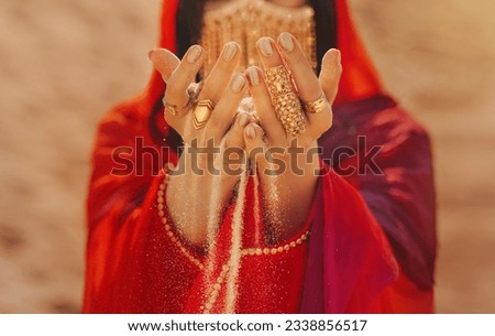 Mystery arabic woman beauty golden mask veil niqab hide face hands close-up with gold metal rings jewelry. Fantasy girl art photo fashion model red dress abay asilk scarf. Sand dunes desert