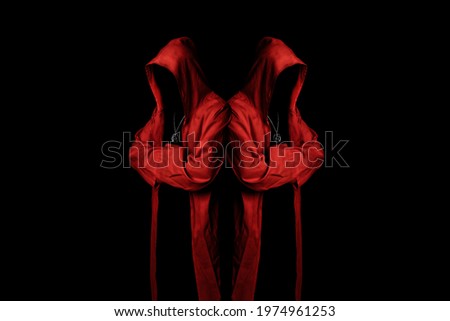 Mystery cult members in a red hooded cloaks in the dark. Unrecognizable person. Hiding face in shadow. Ghostly figure. Sectarian. Conspiracy concept.	