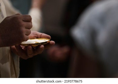 The mystery of faith. Close up of a Catholic priest serving mass and the bread of holy eucharist at communion. Darkened background but lightened host or eucharistic wafer and brass vessel - Shutterstock ID 2193778675