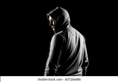 Mystery fitness man posing with grey hoodie on a black background 