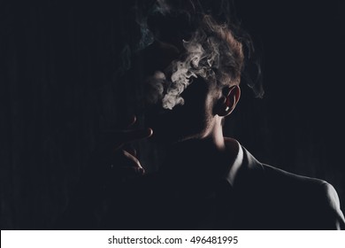 Mystery man with cigar and smoke isolated on black background