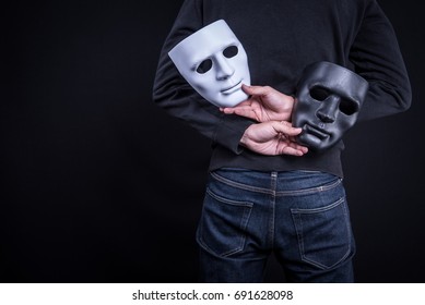 Mystery man holding black and white mask. Anonymous social masking concept. - Shutterstock ID 691628098