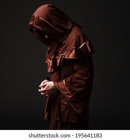 Mystery monk praying on kneels in dark